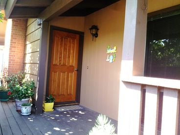 Up a few steps to the front door, lovely garden landscape surrounding the entrance steps, privacy.